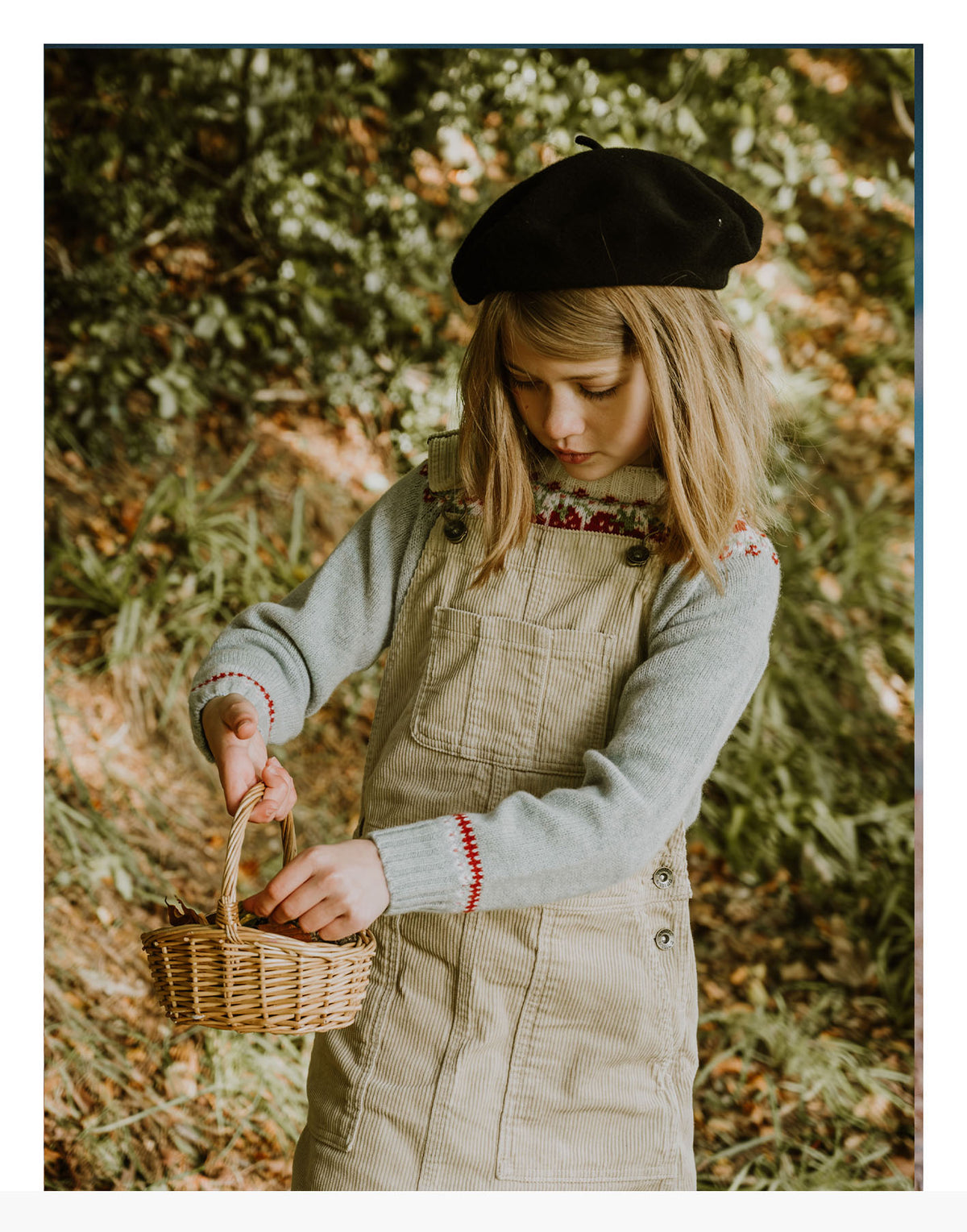 Girl picking berries in the woods in a Little Bosie Strawberries Fair Isle yoke jumper