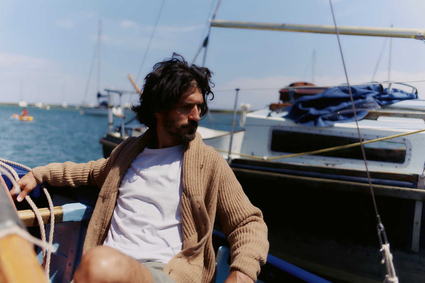 Man on boat wearing a Bosie Blue Mogganer Harbourmaster Cardigan in Sanday Camel